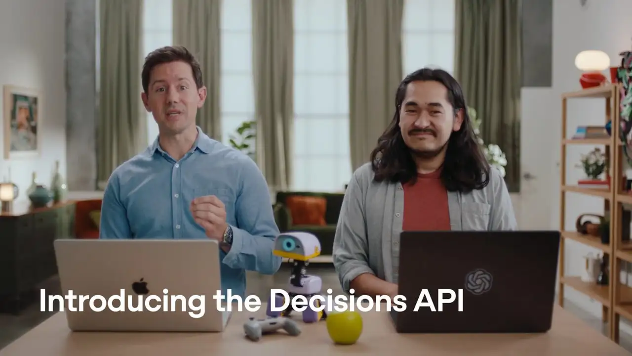 OpenAI’s original Decisions API video poster shows two presenters demonstrating the product at laptops.